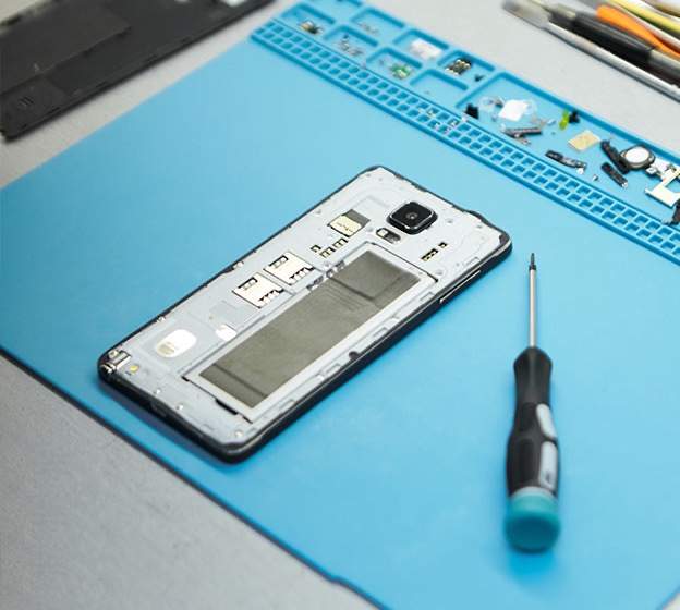 Geöffnetes Smartphone und Schraubendreher auf einer Reparaturmatte